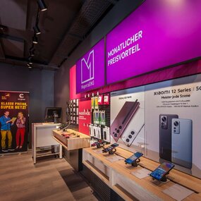 Modernes Telekom-Shop-Innenraum mit Smartphones, Zubehör und MagentaEINS-Tarifangeboten.